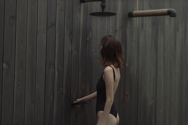 Girl in black swimsuit under the shower